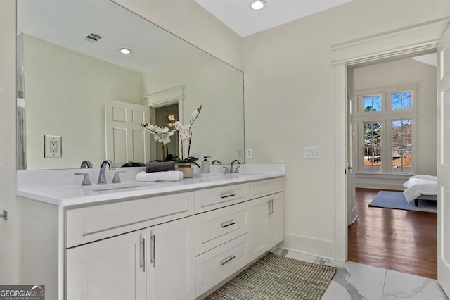 ensuite bathroom with marble finish floor, baseboards, visible vents, and a sink