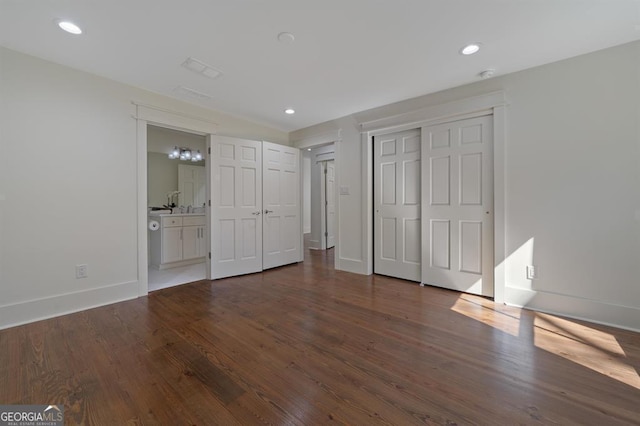 unfurnished bedroom with baseboards, connected bathroom, dark wood-style floors, a closet, and recessed lighting