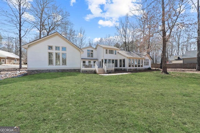 rear view of house featuring a wooden deck, fence, and a yard