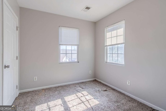 spare room with carpet flooring, visible vents, and baseboards