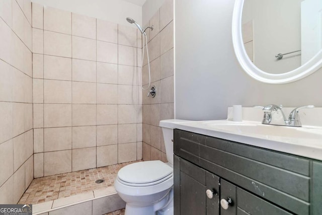 bathroom featuring tiled shower, vanity, and toilet