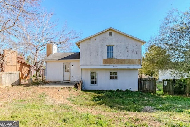 rear view of house with fence, a chimney, and a patio