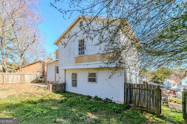 back of property featuring a yard and fence