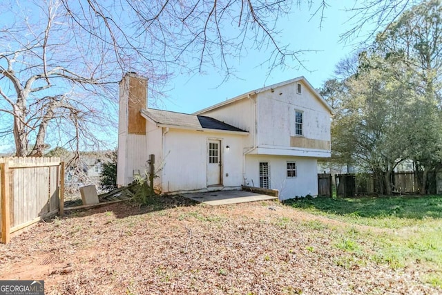 back of house featuring a chimney, a patio area, and fence