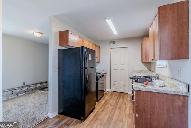 kitchen with light wood-type flooring, light countertops, visible vents, and black appliances