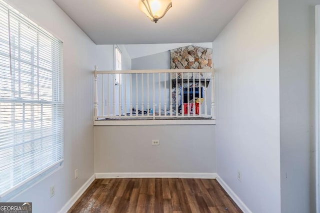 unfurnished room with vaulted ceiling, wood finished floors, and baseboards