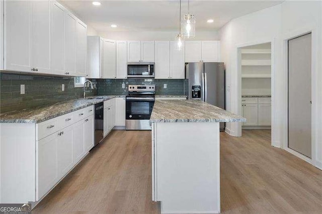 kitchen featuring stone countertops, light wood-style flooring, stainless steel appliances, a kitchen island, and white cabinets