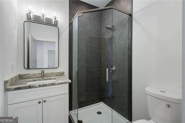 bathroom featuring vanity, a shower stall, and toilet