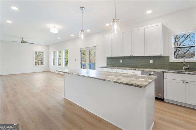 kitchen with french doors, tasteful backsplash, a sink, light wood-type flooring, and dishwasher