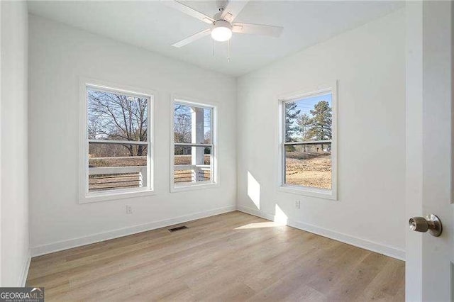 spare room featuring visible vents, light wood-type flooring, a ceiling fan, and baseboards