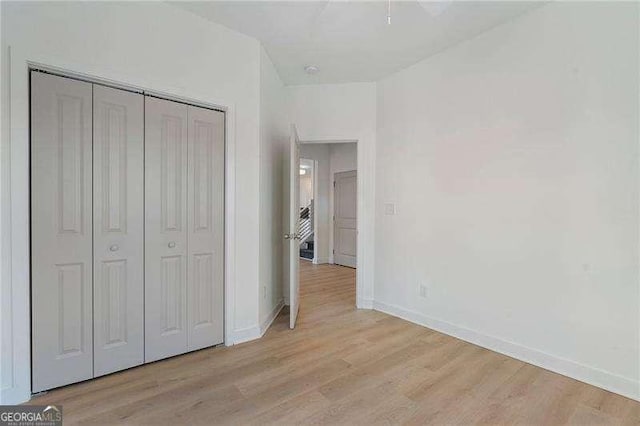 unfurnished bedroom featuring light wood-style floors, a closet, and baseboards