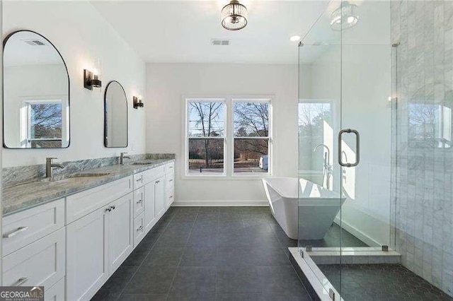 full bath with a sink, visible vents, a soaking tub, tile patterned floors, and double vanity