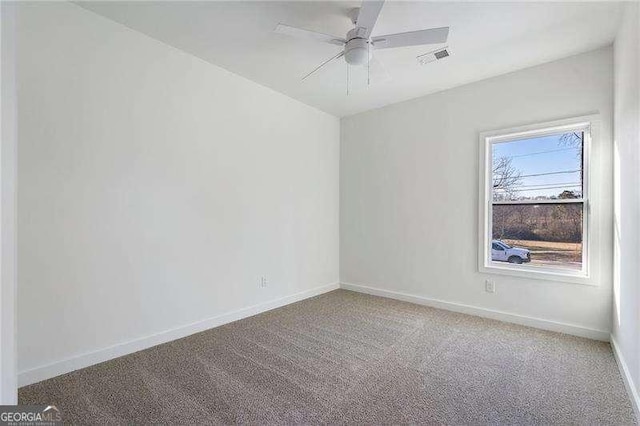 spare room featuring carpet floors, visible vents, ceiling fan, and baseboards