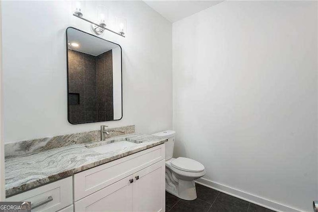 bathroom with toilet, vanity, baseboards, and tile patterned floors