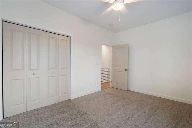 unfurnished bedroom featuring carpet floors, a closet, baseboards, and a ceiling fan