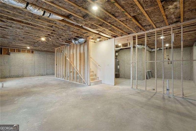 unfinished basement featuring water heater and stairway