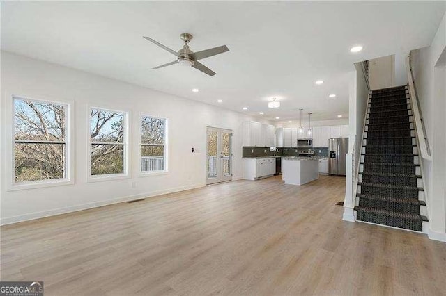 unfurnished living room with recessed lighting, ceiling fan, light wood-style flooring, and stairs