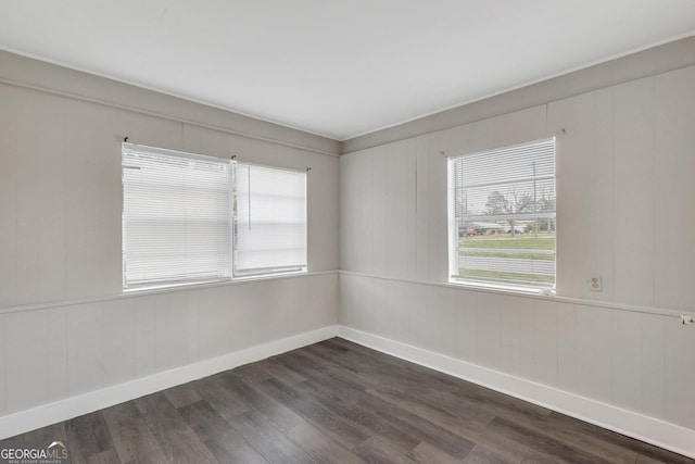 spare room with dark wood-style flooring and baseboards