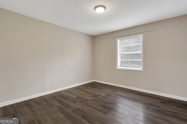 empty room with dark wood-style flooring and baseboards