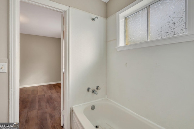 bathroom with baseboards, shower / tub combination, and wood finished floors