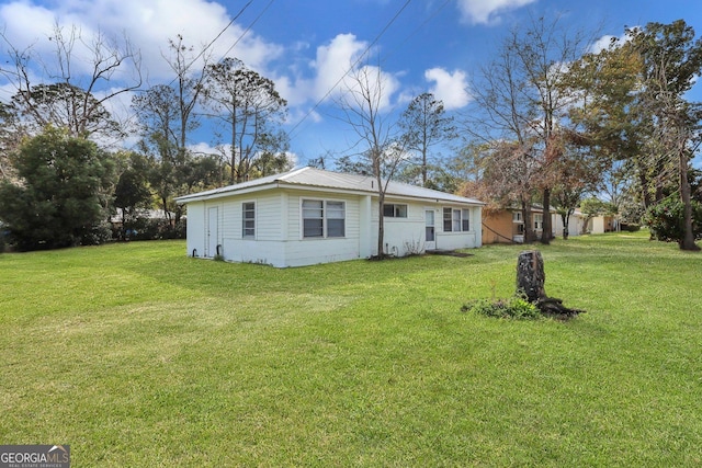 rear view of property with metal roof and a yard