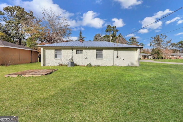 back of property featuring metal roof, a lawn, and brick siding