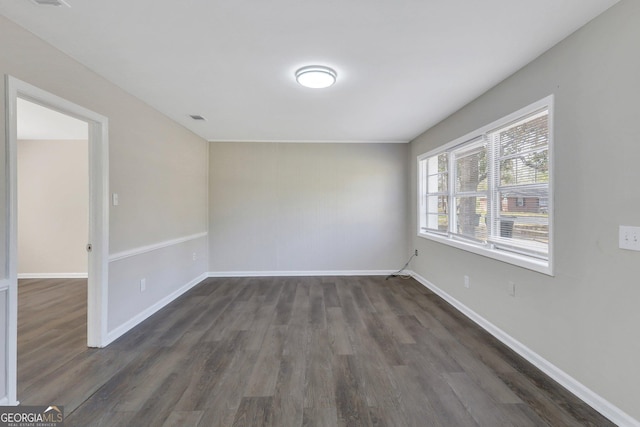 unfurnished room with dark wood-style flooring and baseboards