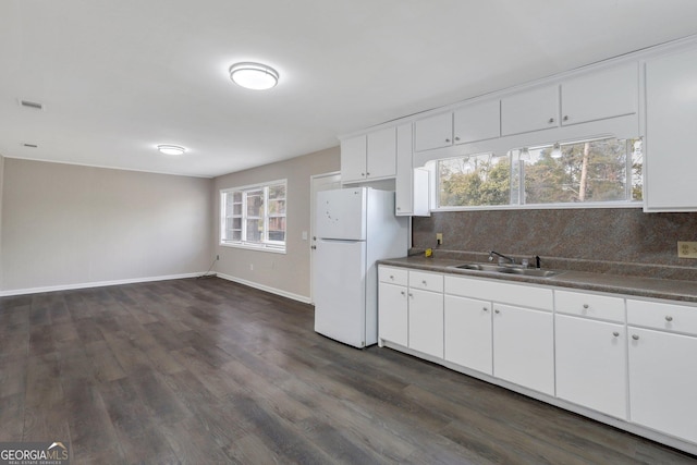 kitchen featuring tasteful backsplash, dark countertops, a sink, and freestanding refrigerator