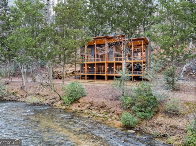 rear view of property featuring a water view and a view of trees