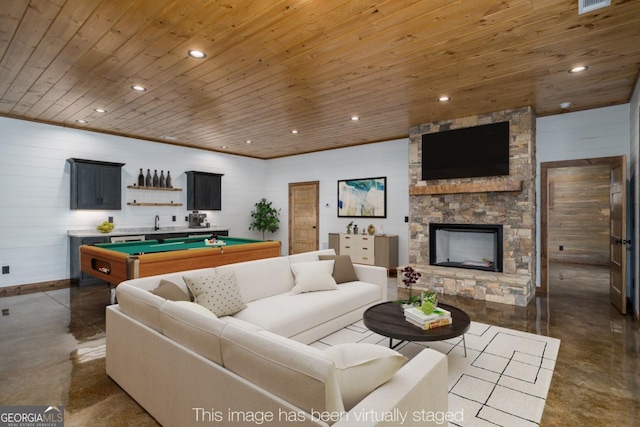 living room featuring a stone fireplace, recessed lighting, billiards, wood ceiling, and finished concrete flooring