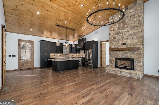 kitchen featuring wooden ceiling, dark cabinets, open floor plan, light countertops, and custom range hood