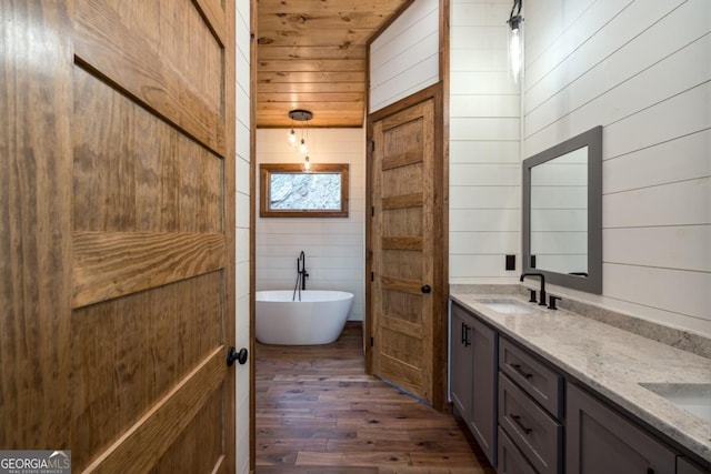 full bath with double vanity, a soaking tub, wood ceiling, a sink, and wood finished floors