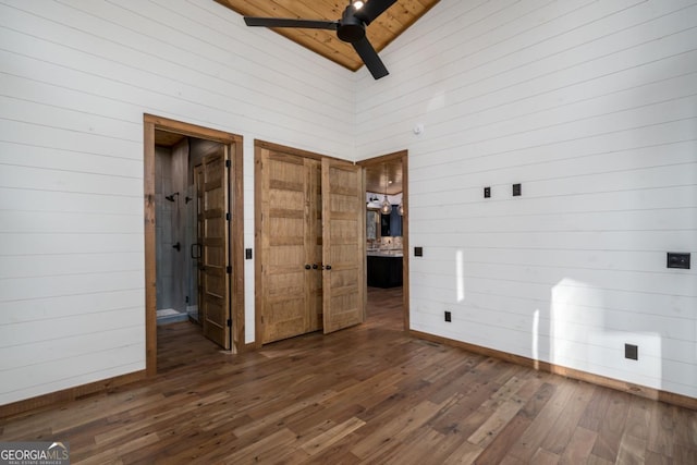 unfurnished bedroom featuring high vaulted ceiling, wood ceiling, wood walls, and hardwood / wood-style floors