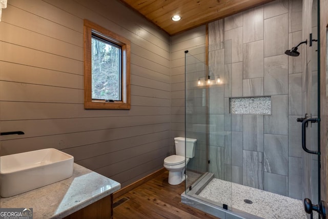 bathroom featuring recessed lighting, toilet, a stall shower, a sink, and wood finished floors