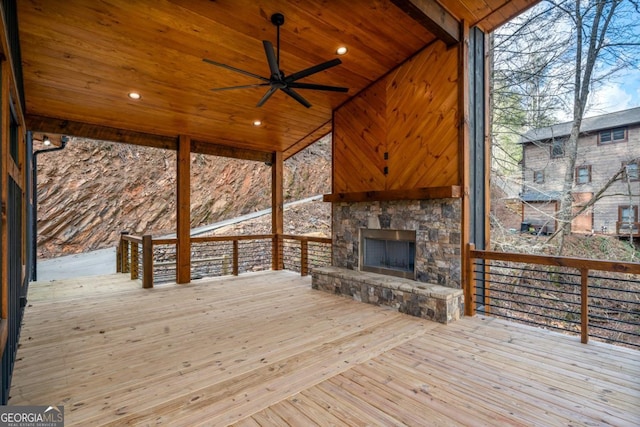 wooden deck featuring ceiling fan and an outdoor stone fireplace