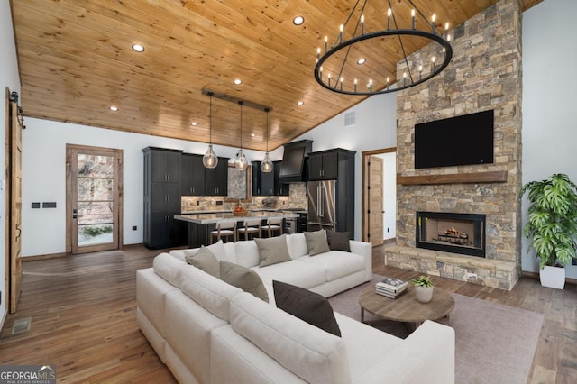 living area featuring visible vents, a stone fireplace, wood finished floors, high vaulted ceiling, and wooden ceiling