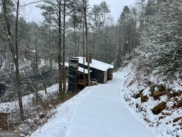 snowy aerial view with a wooded view