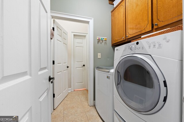 laundry room featuring light tile patterned floors, washing machine and dryer, and cabinet space