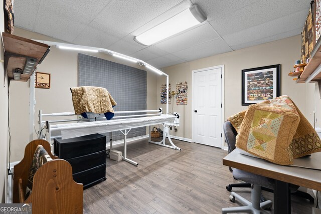 office featuring a paneled ceiling, baseboards, and wood finished floors