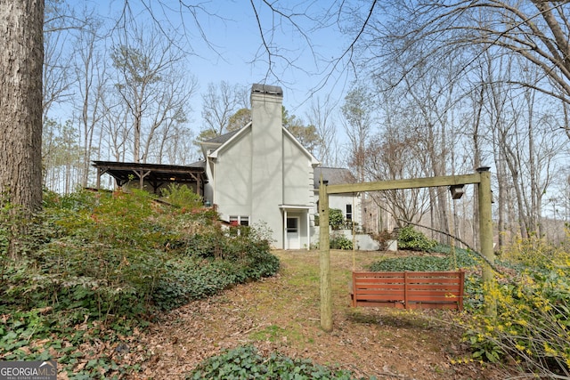 rear view of house featuring a chimney and stucco siding