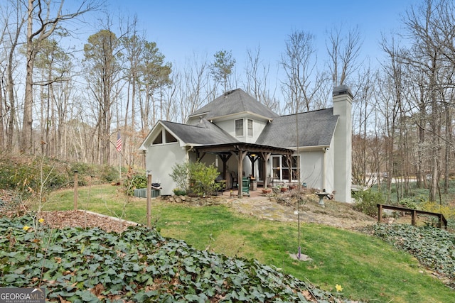 view of front facade with a patio, a chimney, stucco siding, a front yard, and a pergola