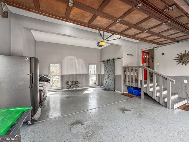 garage featuring a wainscoted wall, freestanding refrigerator, and a garage door opener