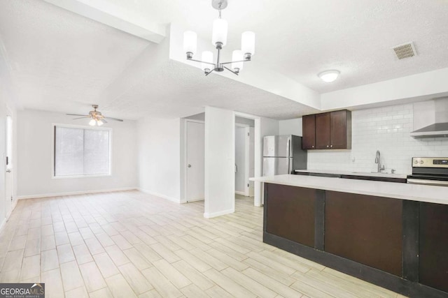 kitchen featuring visible vents, light countertops, appliances with stainless steel finishes, wall chimney range hood, and tasteful backsplash