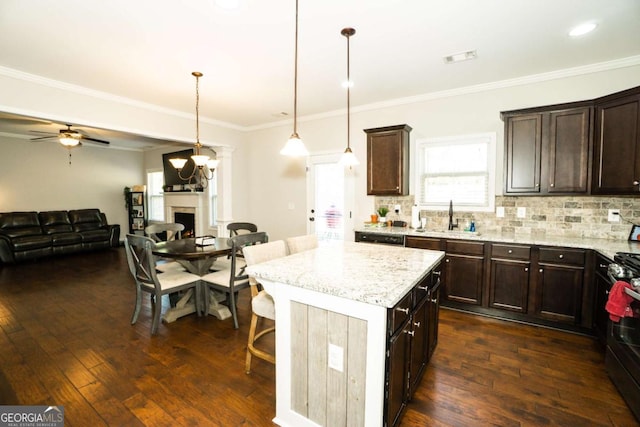 kitchen with a warm lit fireplace, a sink, backsplash, and dark brown cabinets