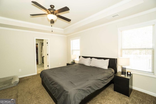 bedroom featuring a tray ceiling, multiple windows, and crown molding