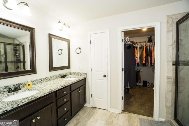 full bath featuring double vanity, a shower stall, a walk in closet, and a sink