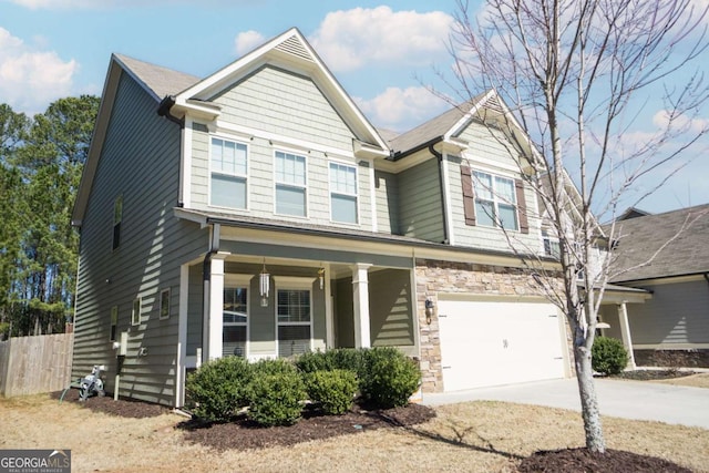 craftsman inspired home with a garage, concrete driveway, stone siding, fence, and a porch