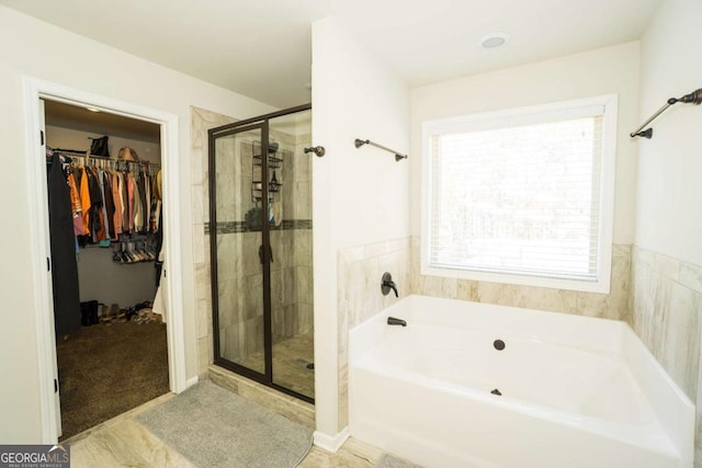 full bathroom featuring a stall shower, a walk in closet, and a bath