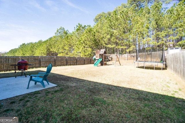 view of yard with a trampoline, a playground, a patio, and a fenced backyard