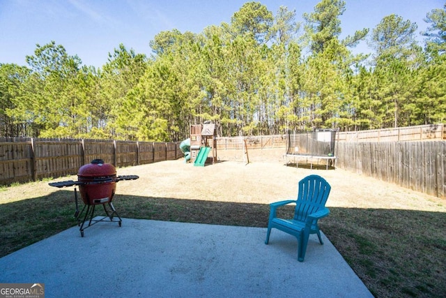 view of patio / terrace featuring a trampoline, a playground, and a fenced backyard